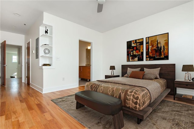 bedroom with baseboards, ceiling fan, ensuite bath, and light wood-style flooring