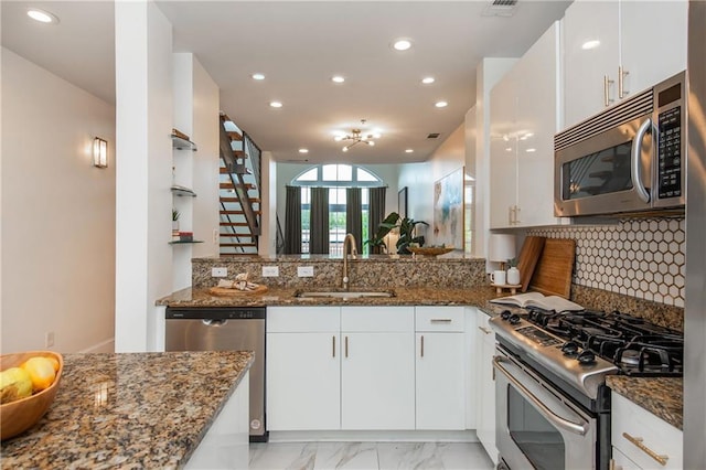 kitchen featuring dark stone counters, stainless steel appliances, recessed lighting, and a sink