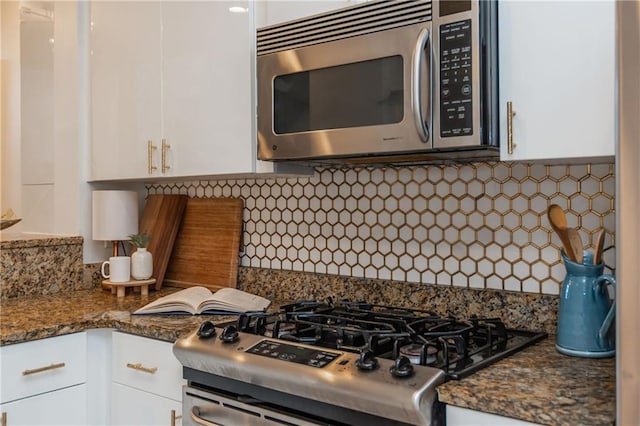 kitchen featuring white cabinetry, dark stone countertops, backsplash, and stainless steel appliances