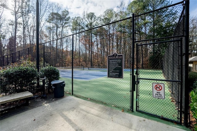 view of tennis court with fence and a gate