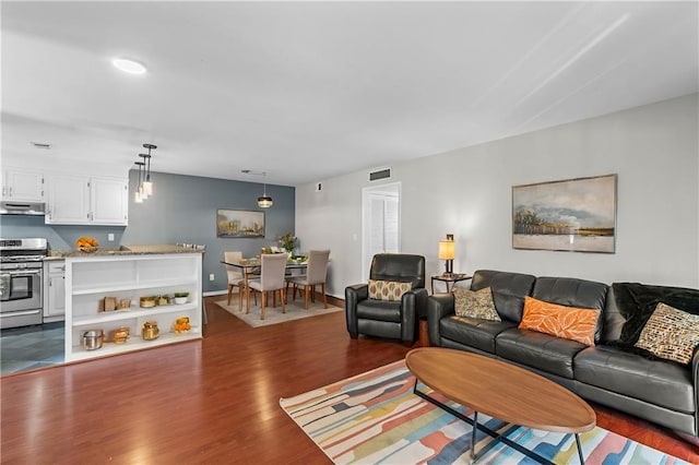 living room featuring dark wood-style floors, visible vents, and baseboards