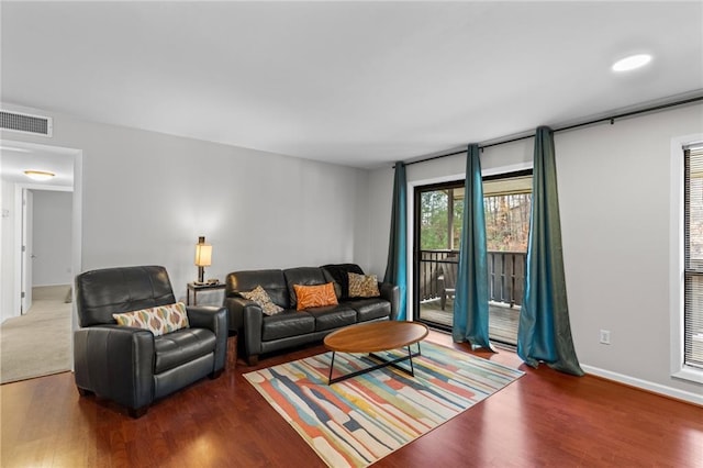 living area with wood finished floors, visible vents, and baseboards