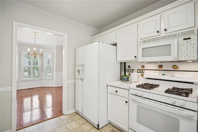 130 White Sands Ct, Suwanee, GA 30024 - kitchen featuring white appliances, a chandelier, white cabinetry, decorative backsplash, and a wainscoted wall