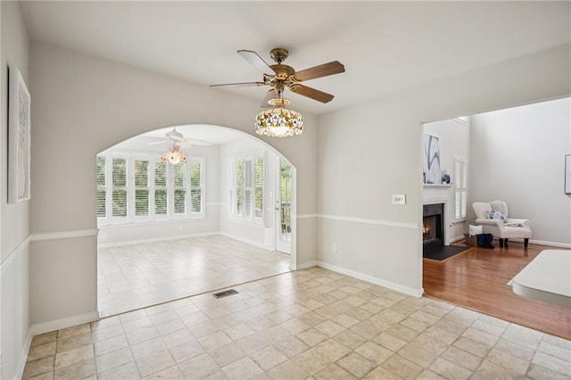 130 White Sands Ct, Suwanee, GA 30024 - empty room featuring a ceiling fan, a fireplace with flush hearth, arched walkways, and light tile patterned floors