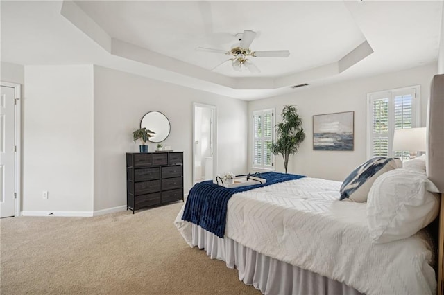 130 White Sands Ct, Suwanee, GA 30024 - carpeted bedroom featuring a tray ceiling, multiple windows, connected bathroom, and ceiling fan