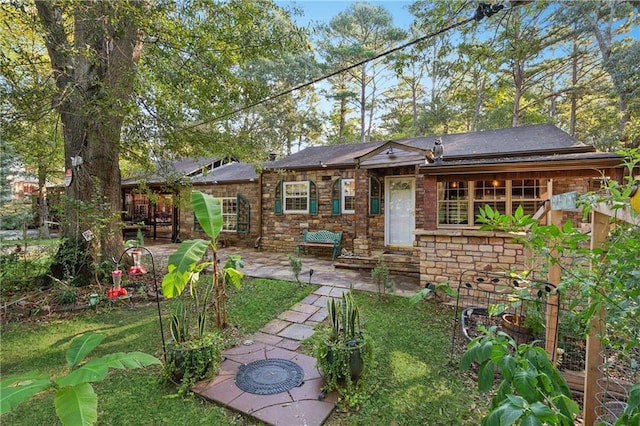 back of property featuring entry steps, stone siding, and a patio