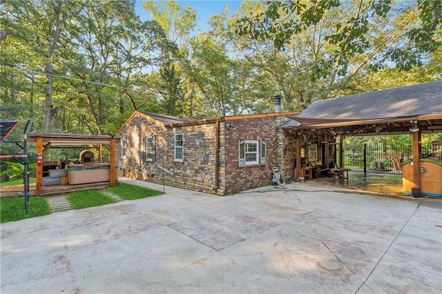 exterior space featuring stone siding, brick siding, and a hot tub