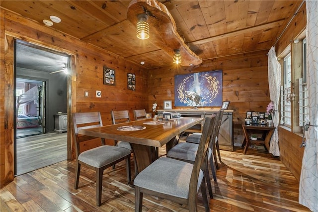 dining space featuring wood walls, wooden ceiling, wood-type flooring, and a ceiling fan