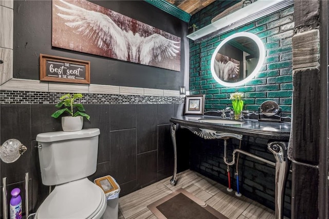 half bathroom featuring a wainscoted wall, tile walls, toilet, and vanity