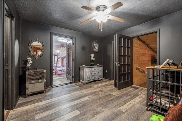 foyer entrance with ceiling fan, a textured ceiling, and wood finished floors