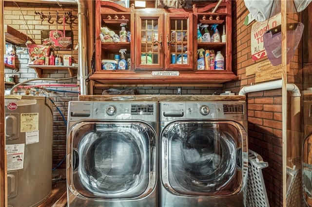 laundry room with laundry area, independent washer and dryer, brick wall, and electric water heater