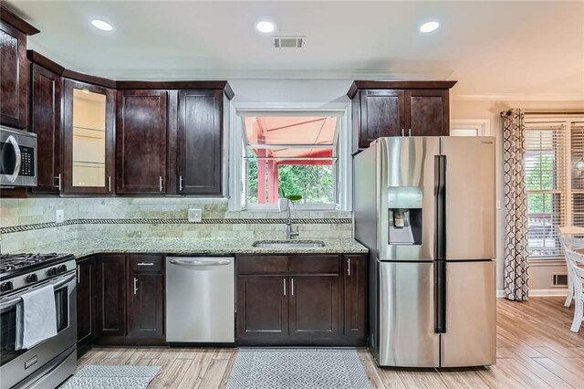 kitchen with appliances with stainless steel finishes, a sink, dark brown cabinetry, light stone counters, and recessed lighting