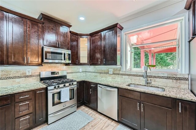 kitchen featuring stainless steel appliances, a sink, decorative backsplash, arched walkways, and light stone countertops