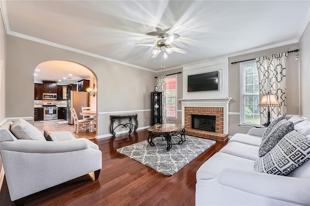 living area with arched walkways, ceiling fan, light wood finished floors, baseboards, and a fireplace