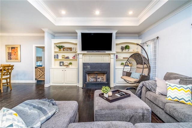 living room featuring a raised ceiling, ornamental molding, dark wood-type flooring, and a high end fireplace