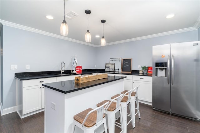 kitchen with stainless steel refrigerator with ice dispenser, a breakfast bar, sink, white cabinetry, and decorative light fixtures