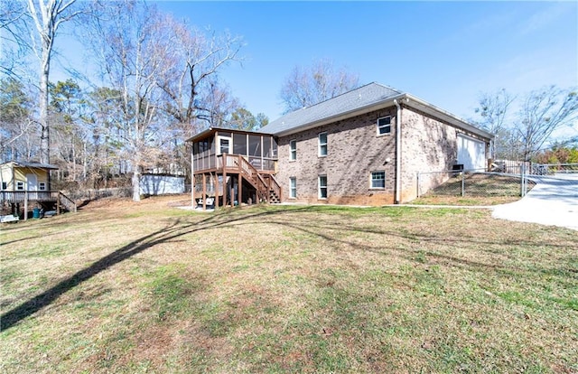 rear view of property featuring a garage, a sunroom, and a lawn