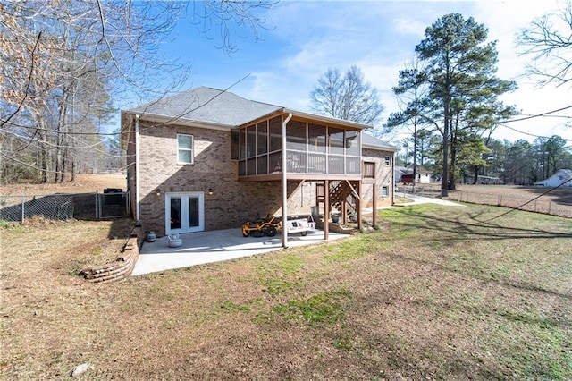 rear view of house featuring a patio, a sunroom, a yard, and french doors