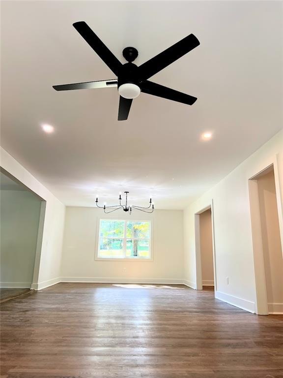 interior space featuring ceiling fan with notable chandelier and dark hardwood / wood-style flooring