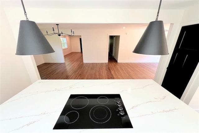 kitchen featuring light stone counters, black electric stovetop, hardwood / wood-style floors, and hanging light fixtures