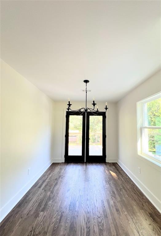 spare room featuring dark hardwood / wood-style flooring and a chandelier