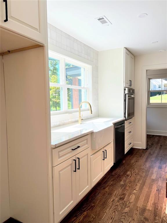 kitchen featuring black dishwasher, sink, white cabinets, oven, and dark hardwood / wood-style flooring