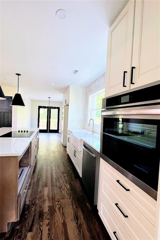 kitchen featuring sink, appliances with stainless steel finishes, white cabinetry, dark hardwood / wood-style flooring, and decorative light fixtures