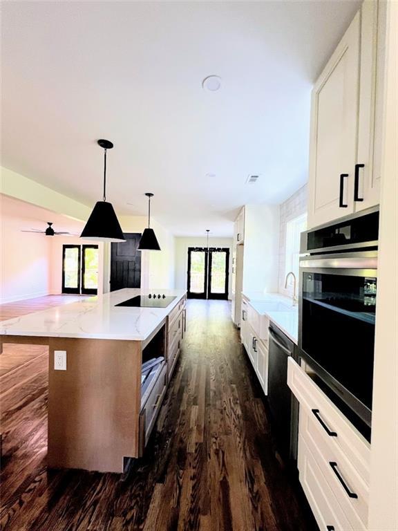 kitchen featuring white cabinetry, pendant lighting, a spacious island, and appliances with stainless steel finishes