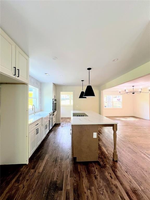 kitchen featuring white cabinetry, decorative light fixtures, light stone countertops, and dark wood-type flooring