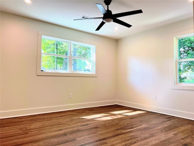 empty room with a healthy amount of sunlight, dark hardwood / wood-style floors, and ceiling fan