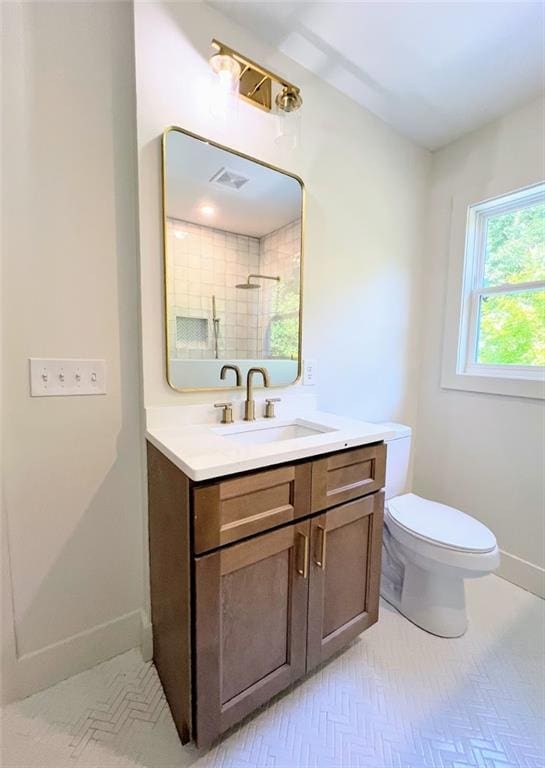 bathroom with a tile shower, vanity, and toilet