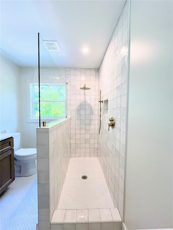 bathroom featuring tiled shower, vanity, toilet, and tile patterned floors