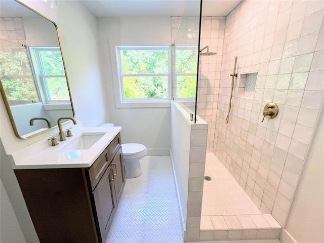 bathroom featuring vanity, tile patterned flooring, plenty of natural light, and tiled shower