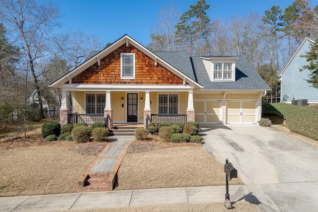 craftsman house featuring a garage, covered porch, driveway, and a shingled roof