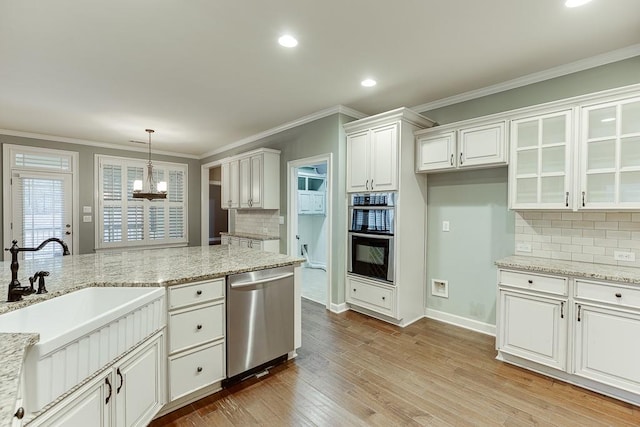 kitchen with a chandelier, light wood-style flooring, white cabinets, stainless steel appliances, and a sink