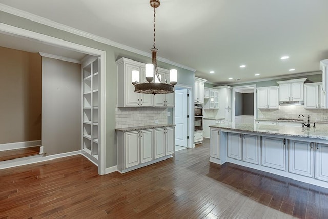 kitchen featuring white cabinetry, crown molding, dark wood-style floors, and under cabinet range hood