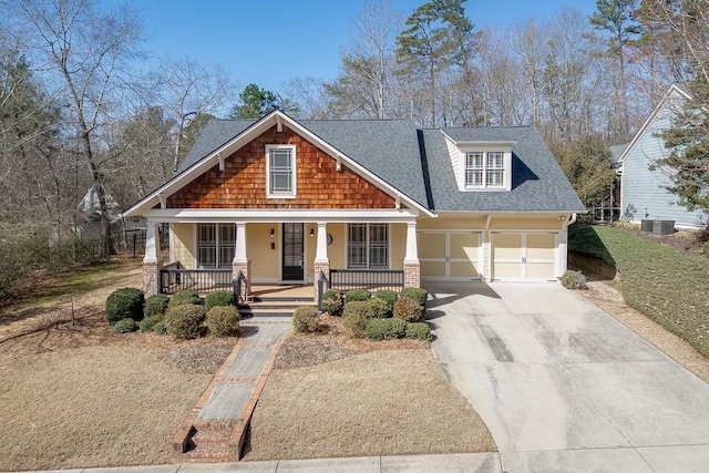 craftsman-style house with cooling unit, roof with shingles, covered porch, and driveway