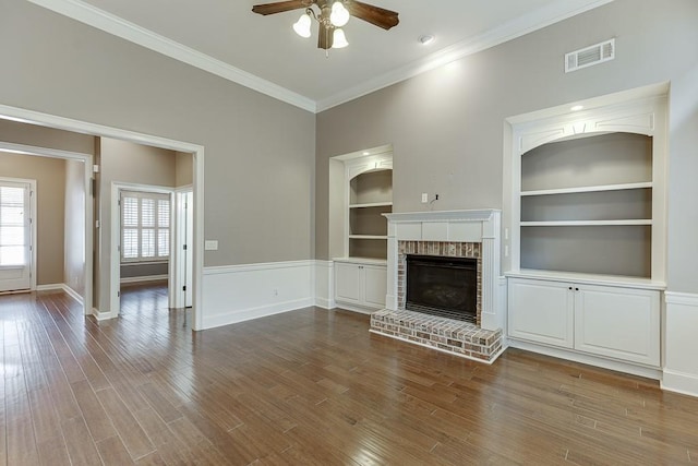 unfurnished living room with visible vents, crown molding, built in features, wood finished floors, and a ceiling fan