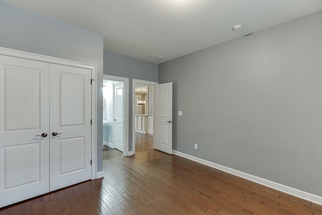 unfurnished bedroom featuring dark wood-type flooring, baseboards, and a closet