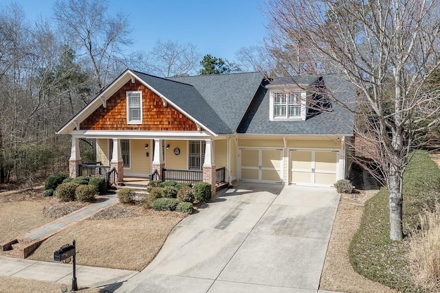 craftsman-style house featuring a garage, covered porch, concrete driveway, and roof with shingles