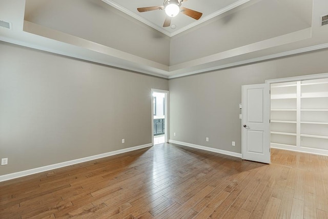 empty room featuring baseboards, wood finished floors, a ceiling fan, and crown molding