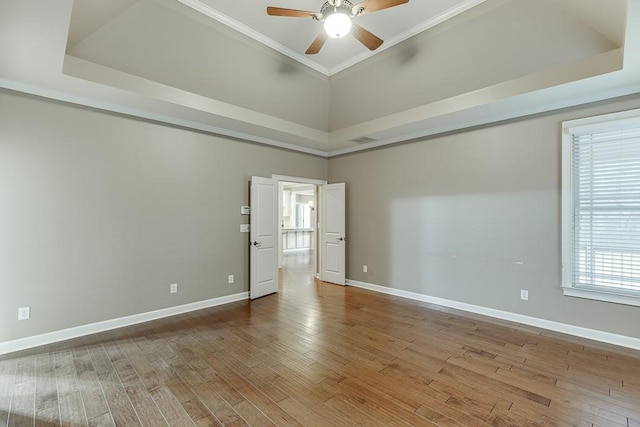 empty room featuring ornamental molding, baseboards, a ceiling fan, and wood finished floors