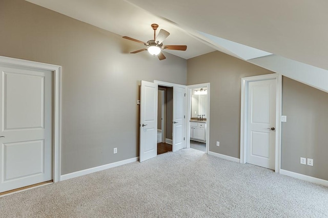 unfurnished bedroom featuring a ceiling fan, ensuite bath, carpet floors, baseboards, and vaulted ceiling