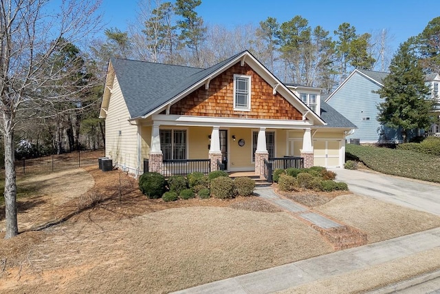 craftsman inspired home with covered porch, concrete driveway, an attached garage, a shingled roof, and brick siding