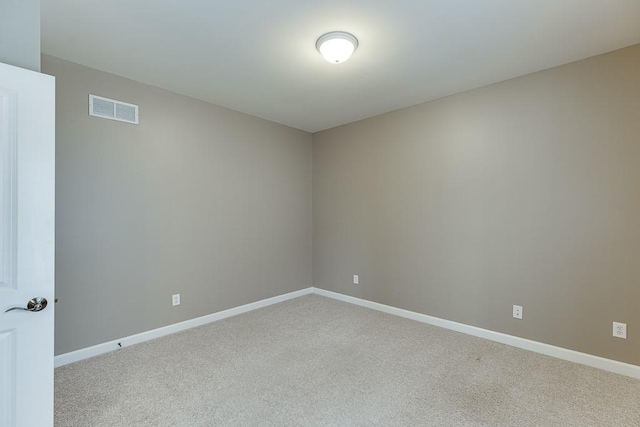 spare room with baseboards, visible vents, and light carpet