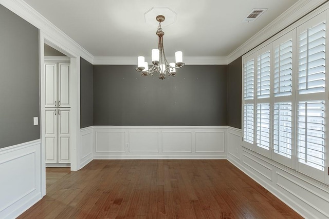 unfurnished room featuring visible vents, dark wood-type flooring, wainscoting, crown molding, and a notable chandelier