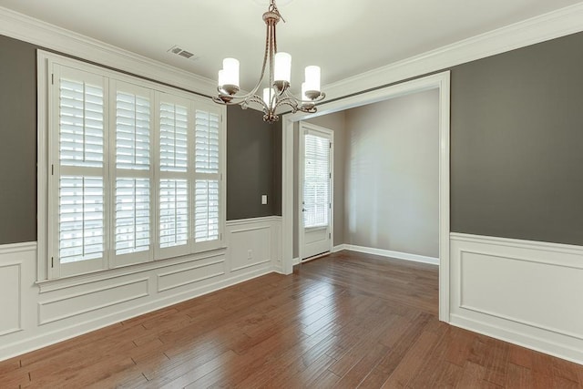 unfurnished dining area with a notable chandelier, wainscoting, visible vents, and wood finished floors