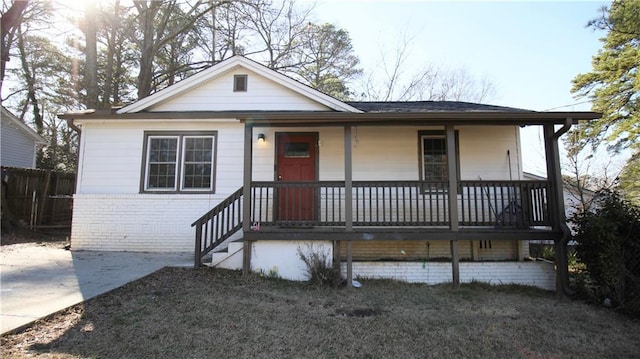 view of front of home with brick siding, a porch, and fence