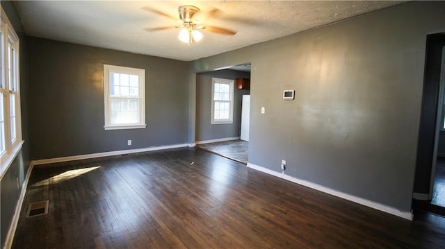 spare room with dark wood-style flooring, visible vents, ceiling fan, a textured ceiling, and baseboards