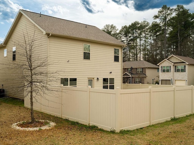 view of side of home with roof with shingles and fence